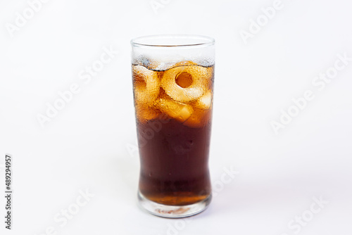 Drinking cola with ice in a clear glass on a white background.