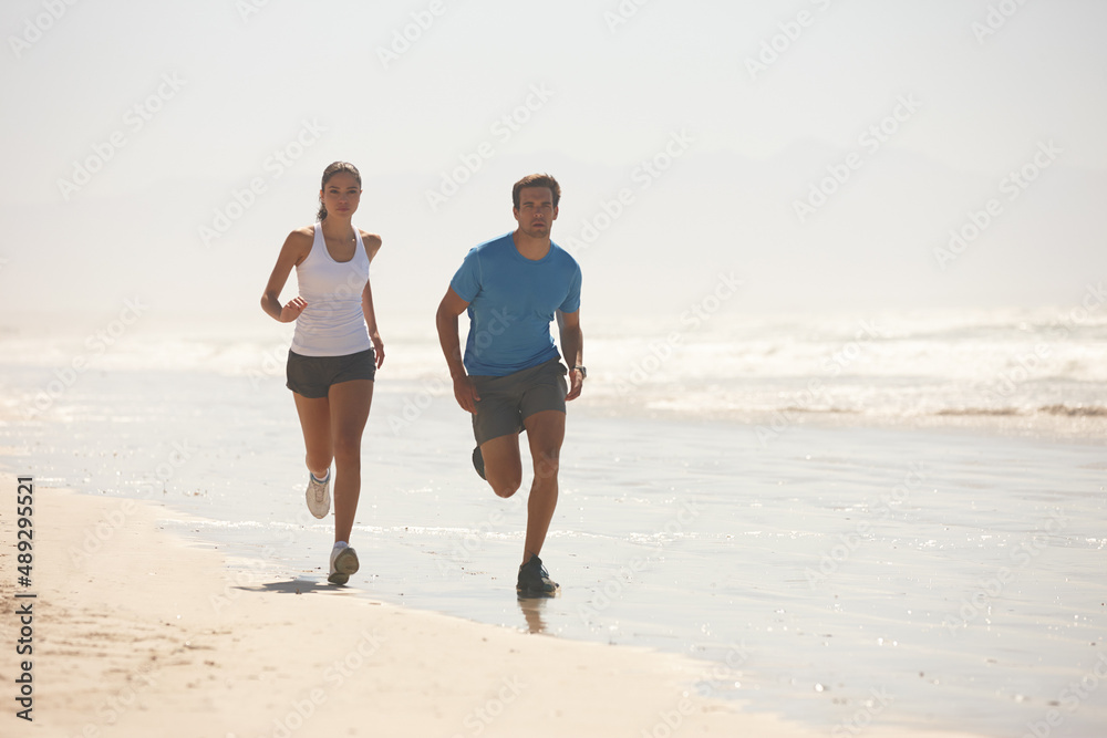 Challenge accepted. Shot of a young couple jogging together on the beach. Challenge accepted. Shot of a young couple jogging together on the beach.