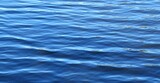 Bright blue water surface with soft waves as a background