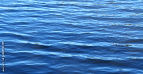 Bright blue water surface with soft waves as a background