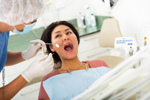 Female patient sitting in dental chair. Dentist is treating female patient
