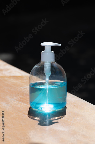 Blue alcohol gel in a pump bottle on a wooden table to wash hands to prevent contagious disease