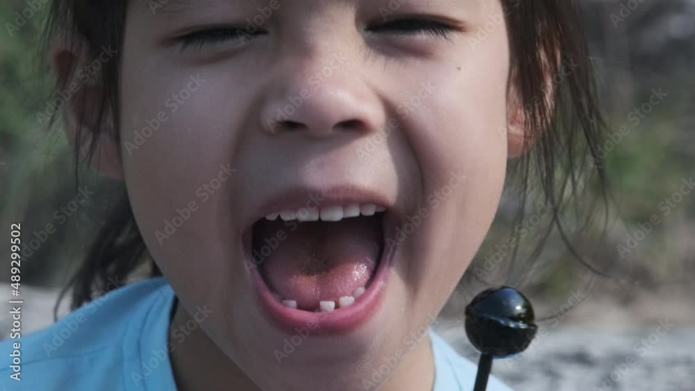 Cute little girl eating lollipops. Happy little Asian girl enjoys eating lollipops. Stock ビデオ | Adobe Stock