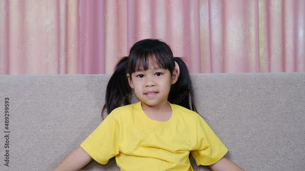 Portrait of a happy smiling little girl sitting on the sofa at home. Portrait of a happy smiling little girl sitting on the sofa at home.