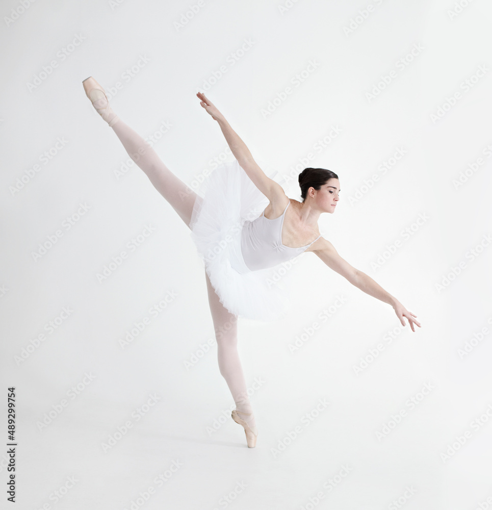 Balance is crucial. Elegant young ballerina dancing en pointe against a white background in penche position.