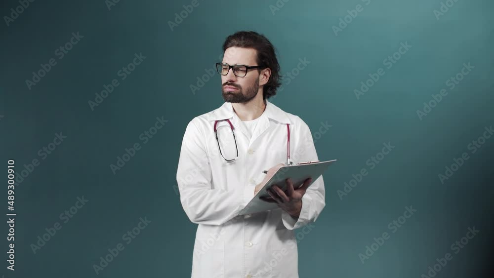 A young doctor in a white gown is writing something down on a tablet keeping in his hands A young doctor in a white gown is writing something down on a tablet keeping in his hands