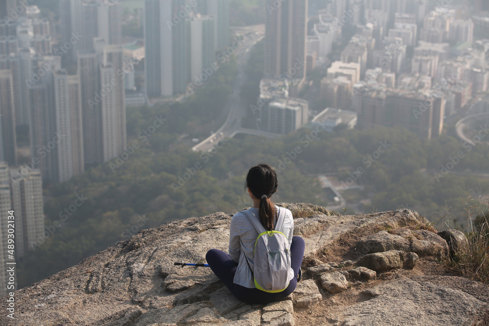 woman sit on the cliff and watch the dense residential housing in hong kong from the view of kowloon