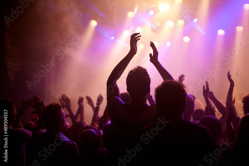 Rock on. Rear view of a music fan dancing with her arms raised at a music concert.