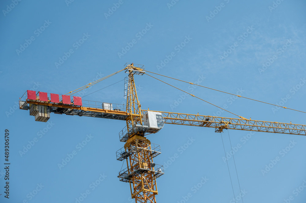 It's a fine day with blue sky, and the tower crane on the high-rise buildings in the city is under construction