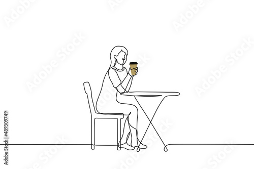 young woman sitting at a round table and drinking from a large cup of coffee - one line drawing vector. coffee to go concept, street cafe