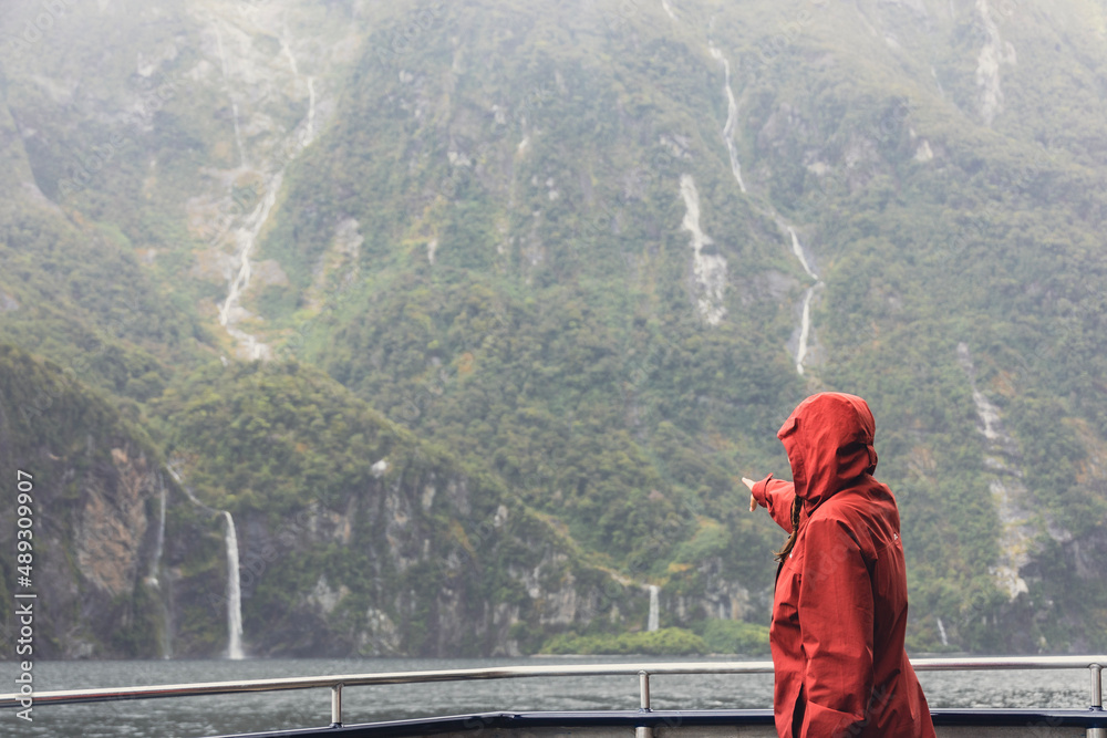 person pointing to a waterfall in the mountains