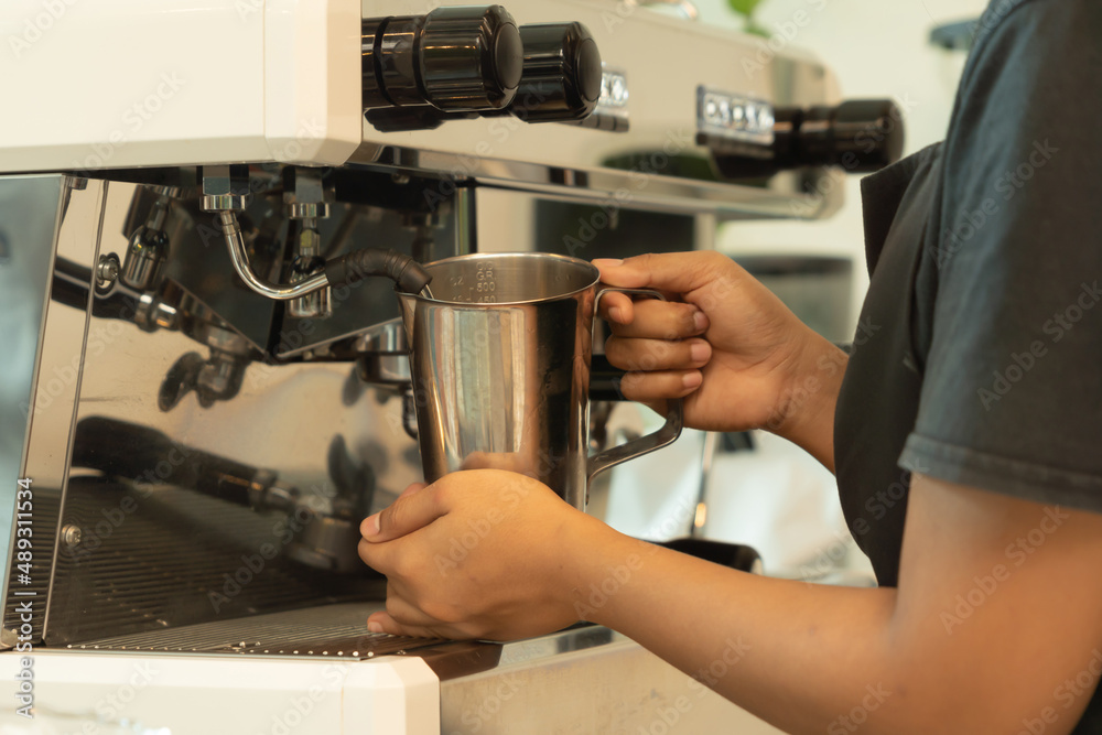 Close up of woman worker, barista in apron making a coffee by using coffee machine in kitchen bar of coffee shop. Business service. People lifestyle. Close up of woman worker, barista in apron making a coffee by using coffee machine in kitchen bar of coffee shop. Business service. People lifestyle.