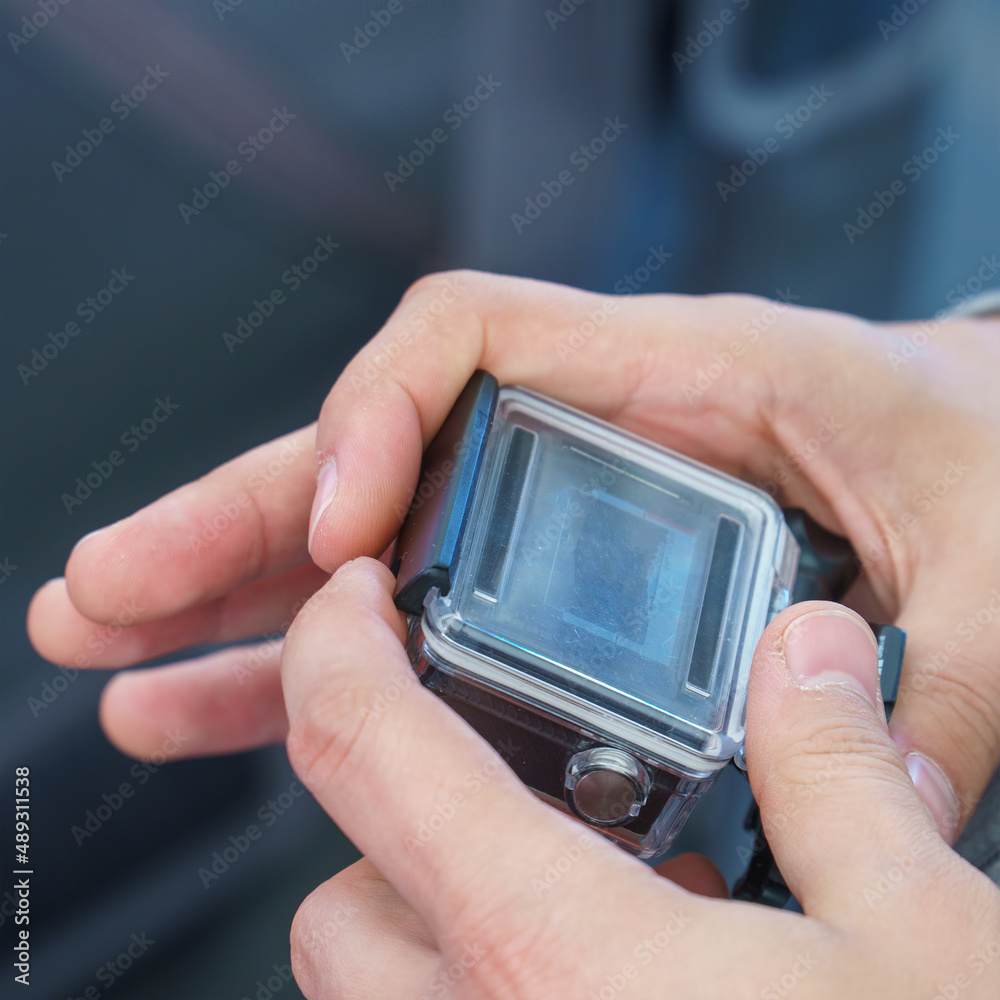 A man holds in his hands and looks through the footage on an action camera A man holds in his hands and looks through the footage on an action camera