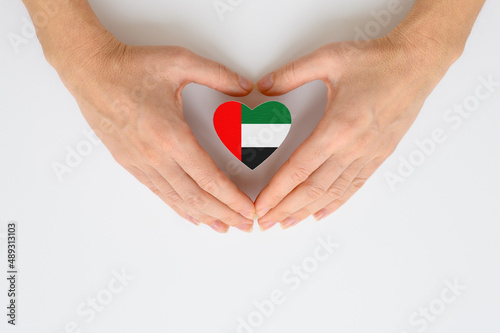 The national flag of UAE in female hands. The concept of patriotism  respect and solidarity with the citizens of the United Arab Emirates.