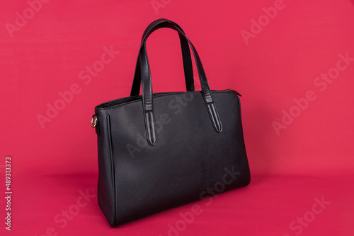 A black leather bag on a red background