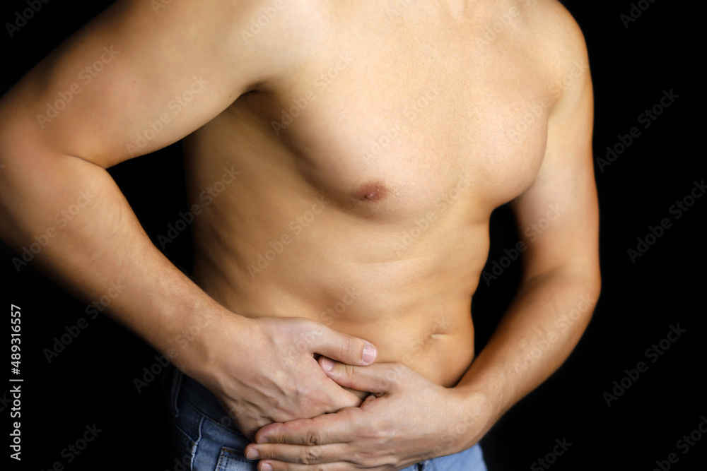 Muscular man with side pain on black background. Person with naked torso suffering from kidney, stomach or pancreas inflammation Muscular man with side pain on black background. Person with naked torso suffering from kidney, stomach or pancreas inflammation