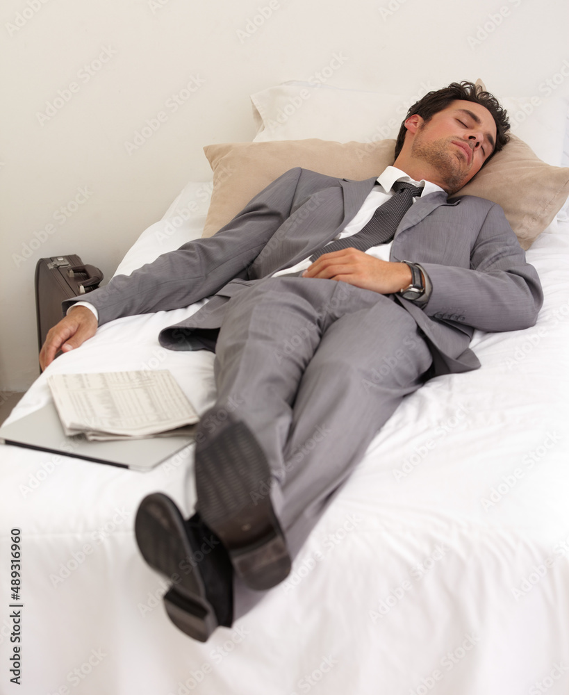 Work really takes it out of you. A handsome young businessman asleep on the bed with his digital tablet.