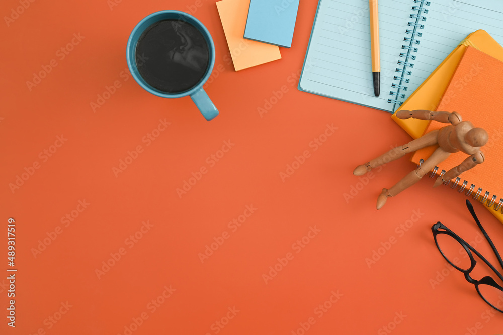 Notebook, sticky notes, eyeglasses, coffee cup on orange background. Flat lay.