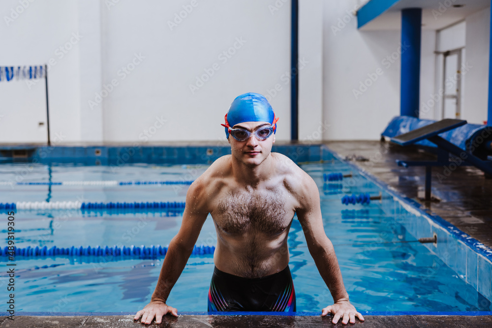 hispanic young man swimmer athlete wearing cap and goggles in a swimming training at the Pool in Mexico Latin America