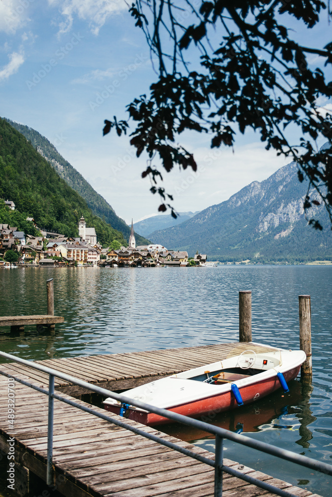 Boat by jetty with Hallstatt by summer lake in Alps in Austria