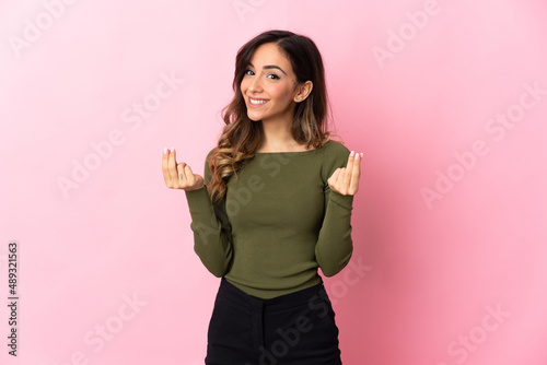 Young caucasian woman isolated on pink background making money gesture © luismolinero