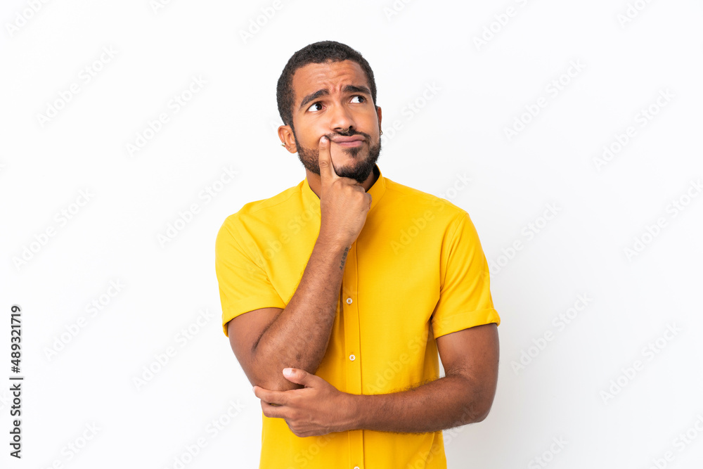 Young Ecuadorian man isolated on white background having doubts while looking up