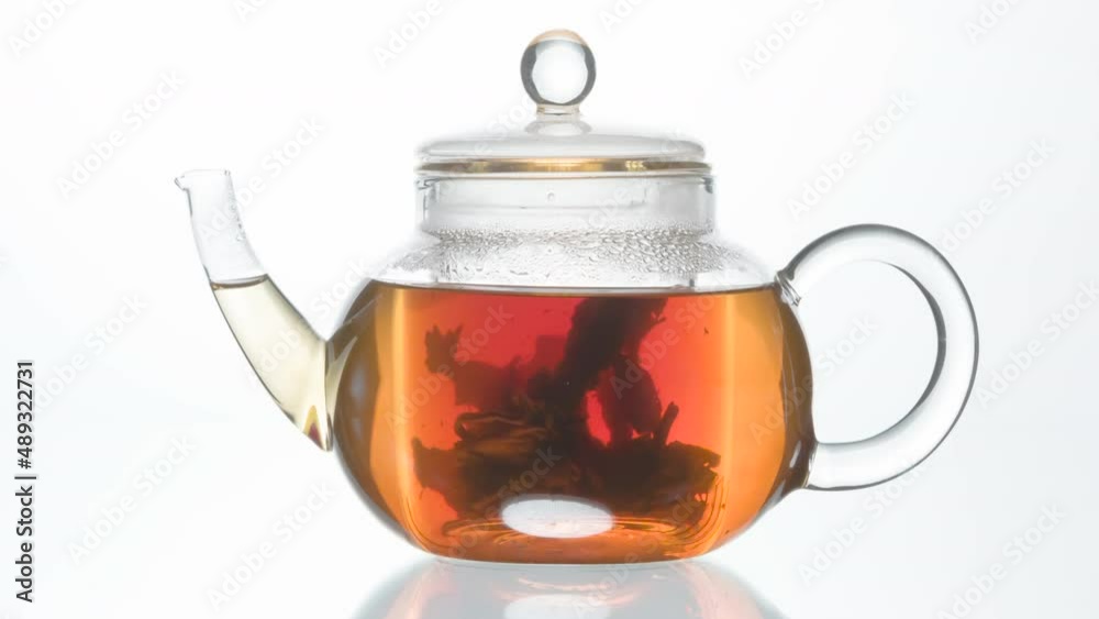 Leaf Tea Swirls in the Kettle. Coarse tea leaves slowly swirl in the hot water of an elegant little glass kettle Leaf Tea Swirls in the Kettle. Coarse tea leaves slowly swirl in the hot water of an elegant little glass kettle