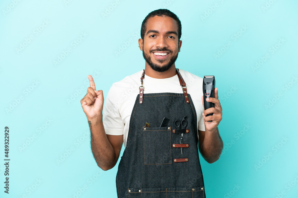 Young hairdresser latin man isolated on blue background showing and lifting a finger in sign of the best Young hairdresser latin man isolated on blue background showing and lifting a finger in sign of the best