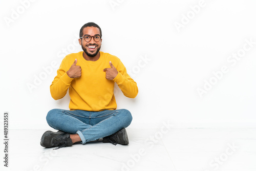 Young Ecuadorian man sitting on the floor isolated on white wall with surprise facial expression