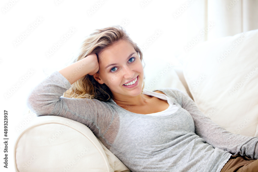 Calm and confident on the couch. Portrait of a young woman relaxing on her couch at home.