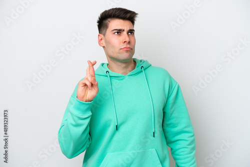 Young caucasian man isolated on white background with fingers crossing and wishing the best © luismolinero