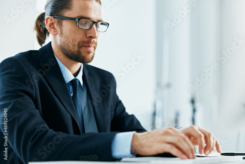 a man in a suit with glasses typing at his desk
