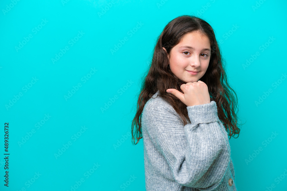 Little girl isolated on blue background pointing to the side to present a product Little girl isolated on blue background pointing to the side to present a product