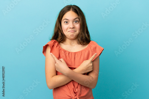 Little caucasian girl isolated on blue background pointing to the laterals having doubts © luismolinero