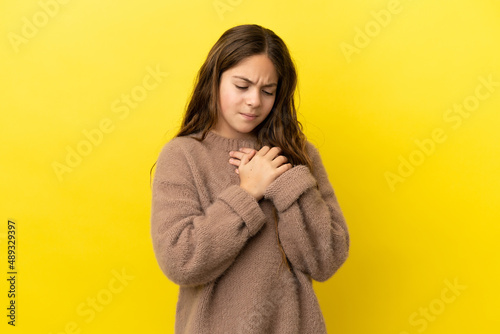 Fotografie Little caucasian girl isolated on yellow background having a pain in the heart
