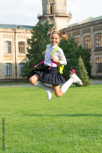 Happy energetic child in uniform back to school jumping for joy, September 1 photo