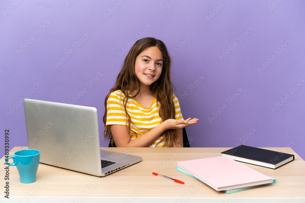 Little student girl in a workplace with a laptop isolated on purple background presenting an idea while looking smiling towards Little student girl in a workplace with a laptop isolated on purple background presenting an idea while looking smiling towards