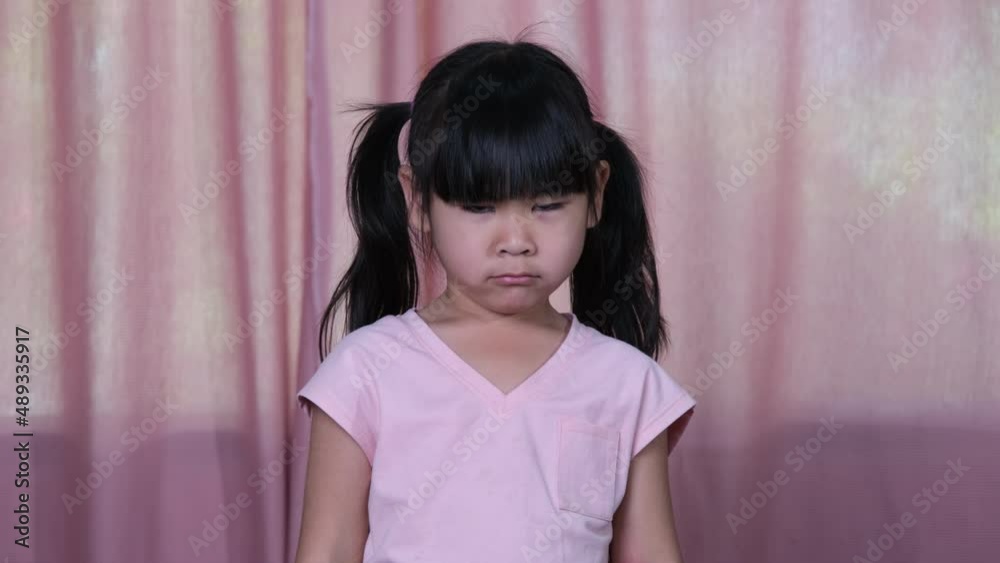 Angry little Asian girl in yellow t-shirt showing disappointment and conflict at home.The concept of facial expressions and gestures Stock ビデオ | Adobe Stock