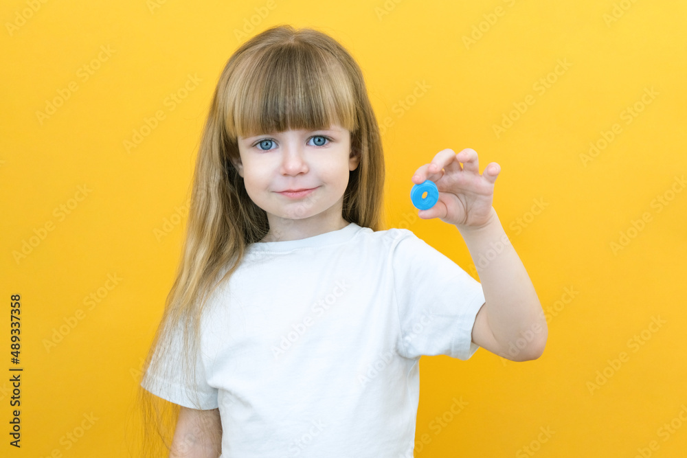 speech therapy. Toddler girl holding the letter O in her hands. Classes with a speech therapist. Girl on isolated yellow speech therapy. Toddler girl holding the letter O in her hands. Classes with a speech therapist. Girl on isolated yellow