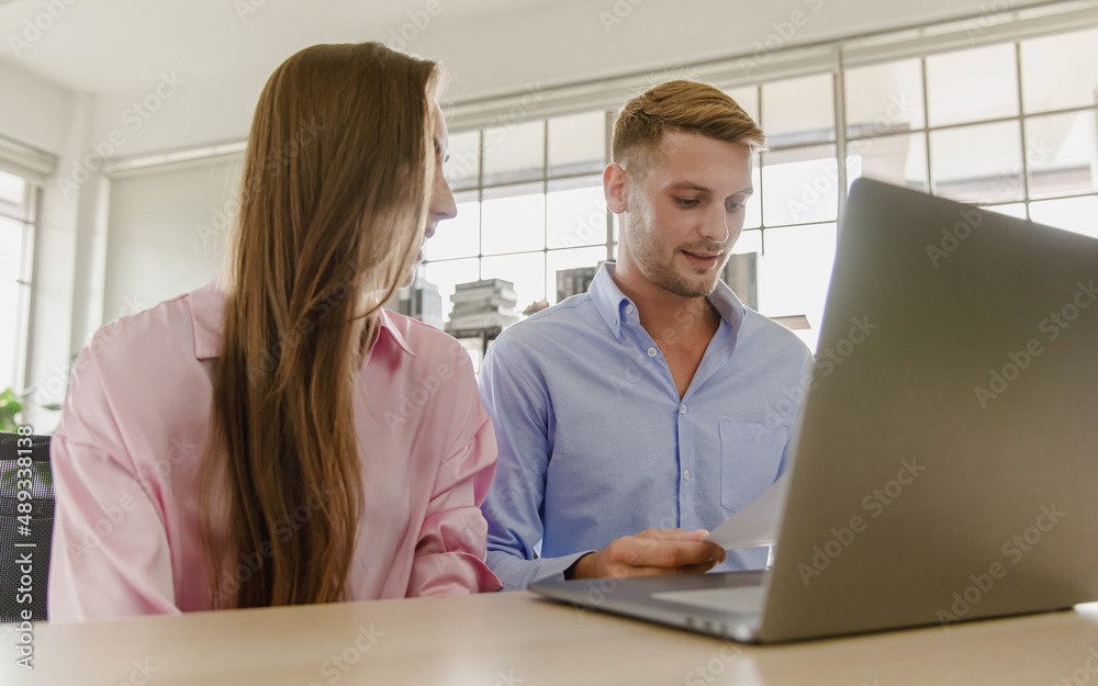 Millennial caucasian lover couple husband and wife in casual outfit sitting smiling on sofa surfing browsing internet shopping online together via laptop notebook computer in living room on weekend Millennial caucasian lover couple husband and wife in casual outfit sitting smiling on sofa surfing browsing internet shopping online together via laptop notebook computer in living room on weekend