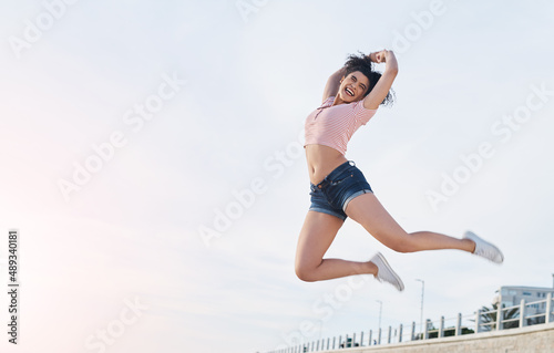 Fototapeta Naklejka Na Ścianę i Meble -  Get out and get loose. Shot of a young woman jumping into mid air at the beach.