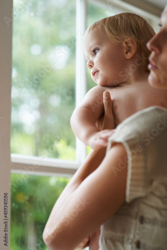 Whats out there. A baby boy and his mother looking out the window.