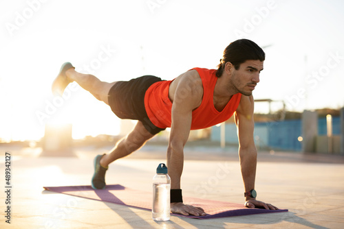 Young muscle man training outside. Fit handsome man doing exercise.