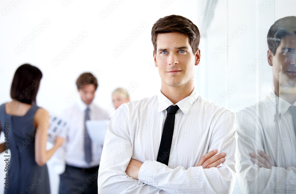 Reflecting on my hard work. Portrait of a handsome executive with his arms folded - blurred colleagues in the background. Reflecting on my hard work. Portrait of a handsome executive with his arms folded - blurred colleagues in the background.