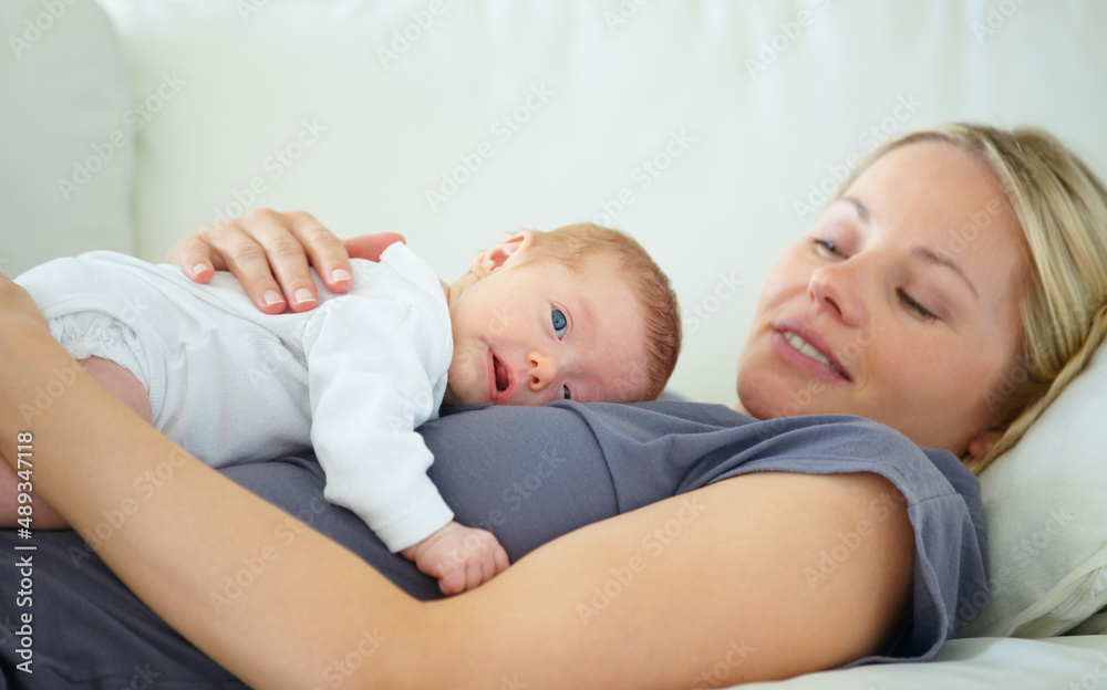 We are too tuckered out. Shot of a mother resting on a sofa with her newborn baby lying on her. We are too tuckered out. Shot of a mother resting on a sofa with her newborn baby lying on her.