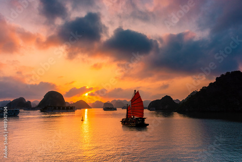 Fototapeta Naklejka Na Ścianę i Meble -  Traditional boat sailing during an amazing sunset over Ha Long Bay, Vietnam