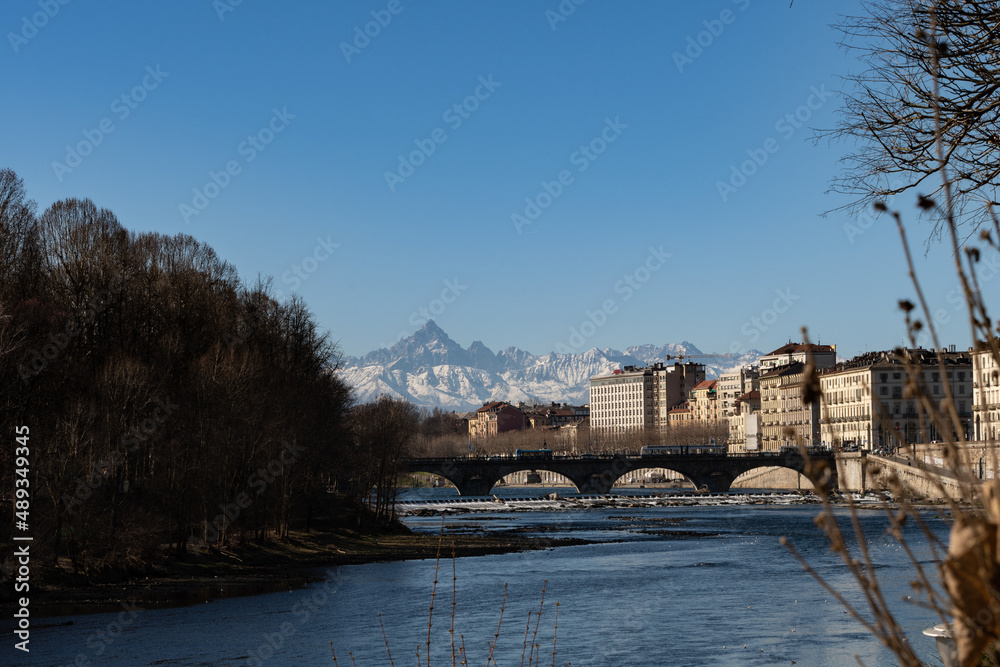 View of the Alps from the city of Torino. Next to the Po' River. Old buildings and Monviso in the background.