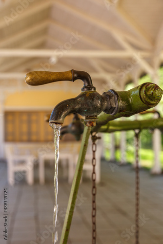 Old water tap with running clean spring water at a spa resort photo