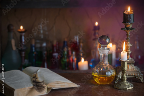 Magic potion, ancient books and candles on dark background photo