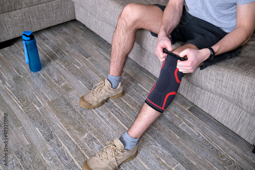 The guy puts a compression bandage on the injured knee. Preparing for sports activities, the sore spot is highlighted in red.